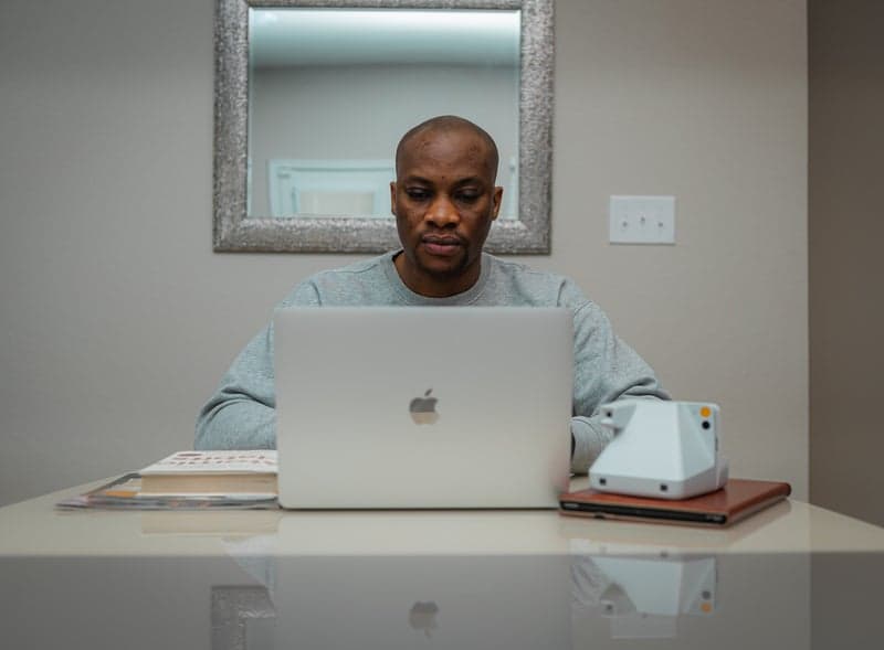 African man working at desk with MacBook