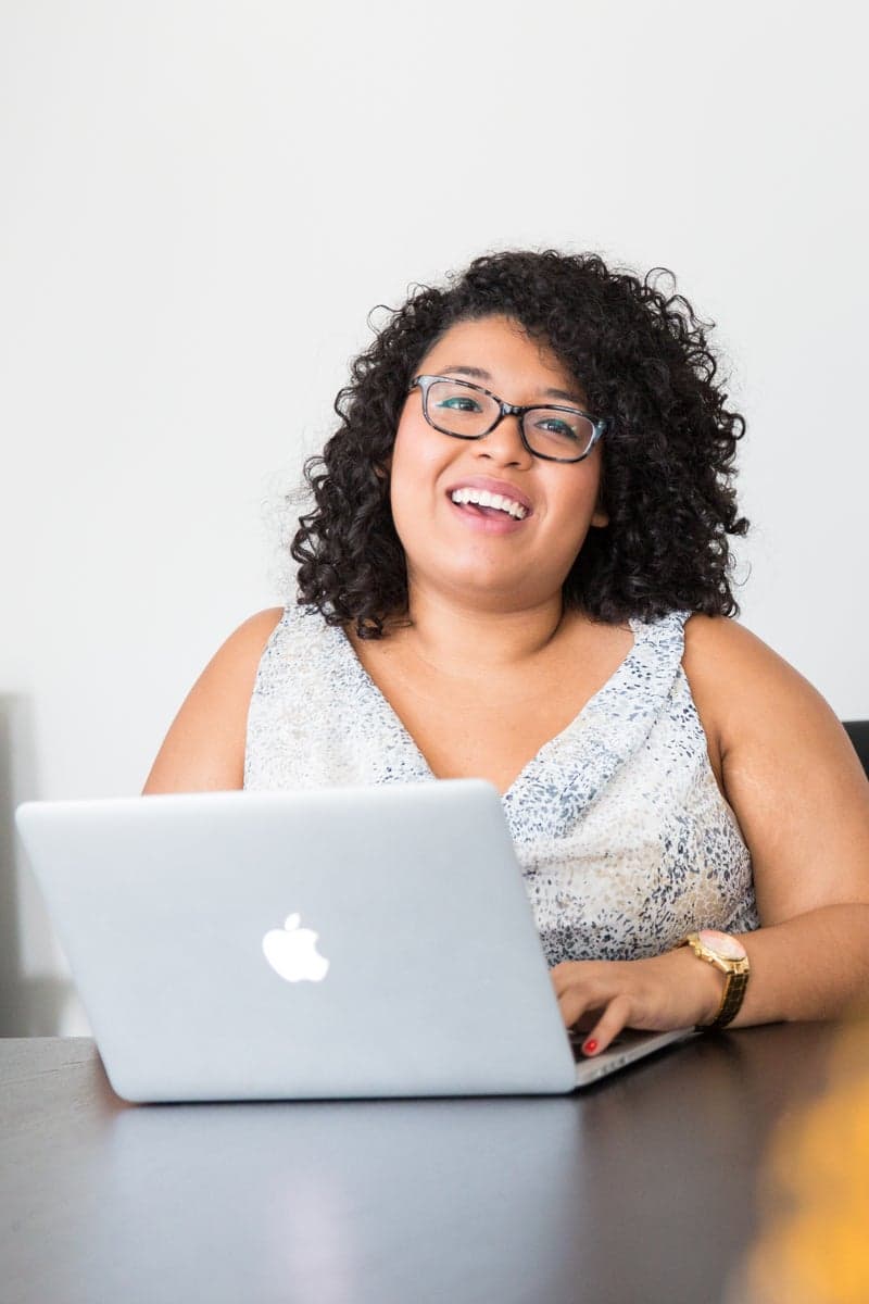 African woman smiling while working on laptop in office